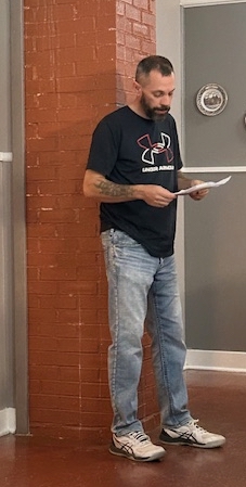 Shane Scales, holding notes, standing